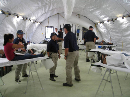 Multiple CAL-MAT people taking care of patients in a tent